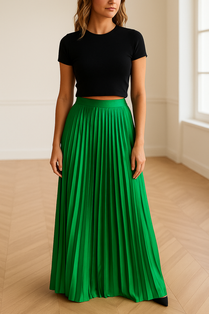 Vrouw draagt een elegante, geplooide maxi-rok in satijnachtige smaragdgroene kleur met glanzende afwerking – high waist en vloeiende pasvorm, perfect voor lente en zomer.