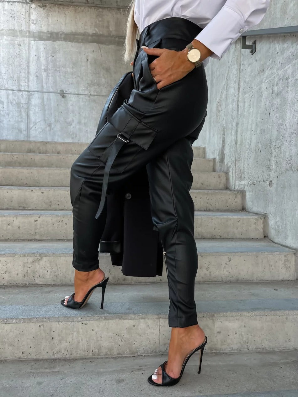 Leandra is een high-waist kunstleren broek met een chique knoop- en ritssluiting en een trendy splitdetail. Het duurzame en comfortabele imitatieleer zorgt voor een strakke, flatterende look die je benen verlengt. Perfect voor een avondje uit of een edgy dagelijkse stijl. Verkrijgbaar in zwart en bruin, maten XS-L. Upgrade je garderobe met Leandra en straal zelfvertrouwen en stijl uit. Bestel nu en maak een statement!