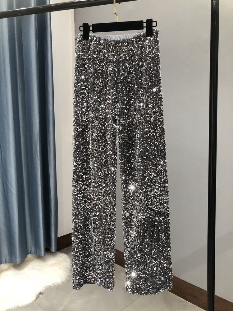 Sienna glitter wijde-pijpen broek: sprankelende glamour en comfort in één. Perfect voor feestdagen, diners of evenementen waar je wilt schitteren. Met een luxueus paillettenontwerp, wijde pijpen voor een chique silhouet en een comfortabele tailleband is deze broek ideaal om een stijlvol statement te maken. Verkrijgbaar in Zilver, Zwart en Zwart/Zilver, in één maat. Bestel nu en geef je garderobe een moderne, elegante touch!